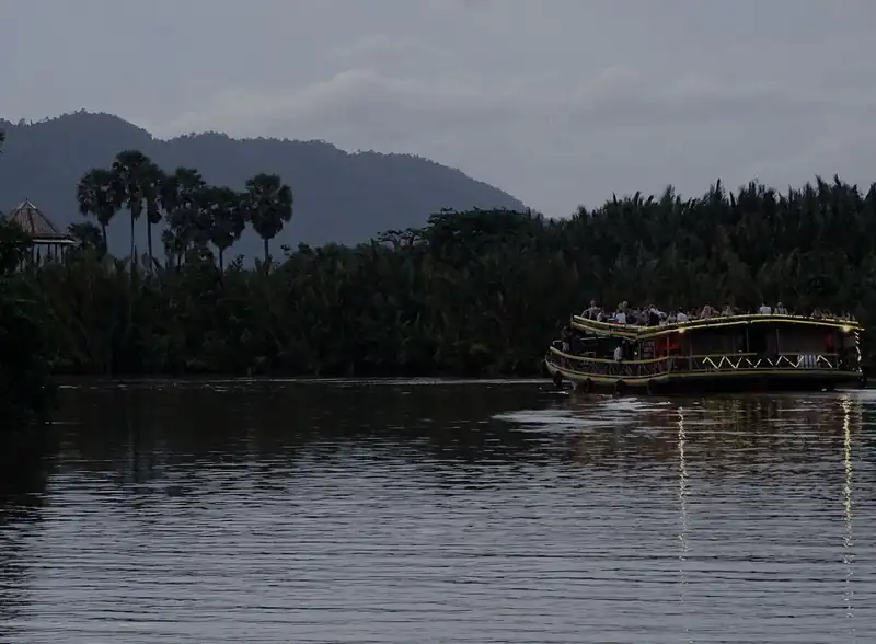 A boat on the Kampot River in the evening, with the hills behind